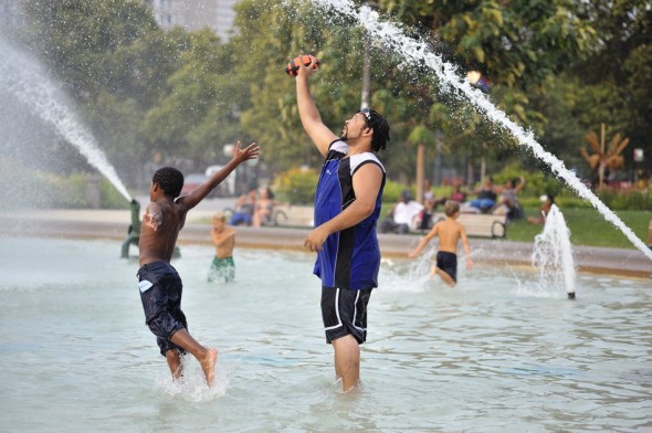 Guys tossing a football in fountain.